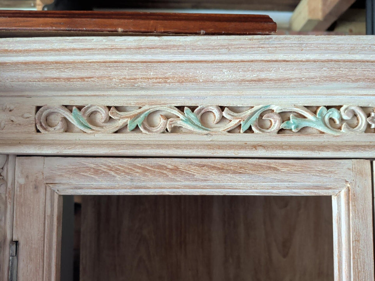 Close-up of carved floral trim and distressed finish on cabinet
