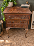 Vintage three drawer wooden chest with cabriole legs styled in a modern vintage interior